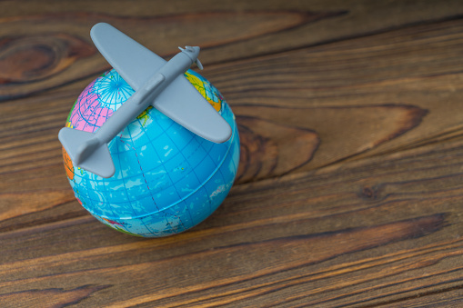 Airplane on the globe, concept air flight, tourism, travel. On a wooden table