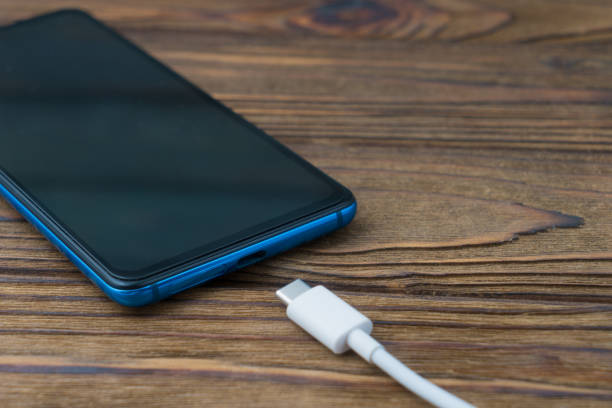 istock Connecting a mobile phone for charging, on a wooden background 1204460518