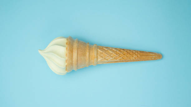 Vanilla ice cream cone on blue faded pastel color background. Vanilla ice cream in wafer cup Vanilla ice cream cone on blue faded pastel color background. Vanilla ice cream in wafer cup. ice cream with wafer rolls stock pictures, royalty-free photos & images
