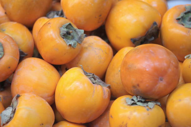 istock Red yellow juicy persimmon lie on a store counter 1204462190