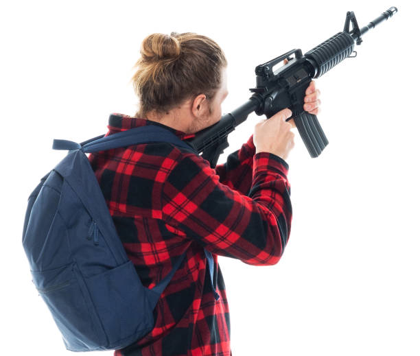 istock Caucasian young male student wearing backpack and holding weapon and using rifle 1204464870
