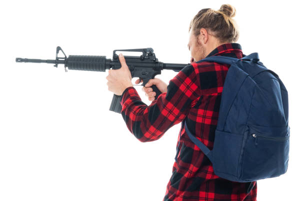 istock Caucasian male university student wearing backpack and holding weapon and using gun 1204465465