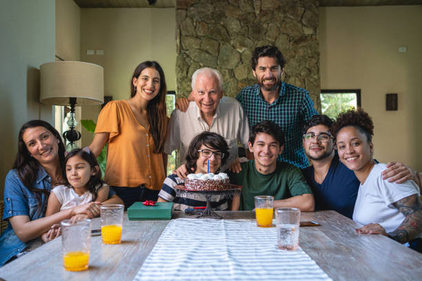 Smiling big Latin family celebrating birthday Cheerful big Latin family celebrating birthday together in grandfather home happy birthday cousin images stock pictures, royalty-free photos & images