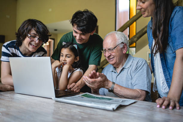 modern grandchildren teaching grandfather in retirement how to use laptop - grandparent using computer laptop dining table imagens e fotografias de stock