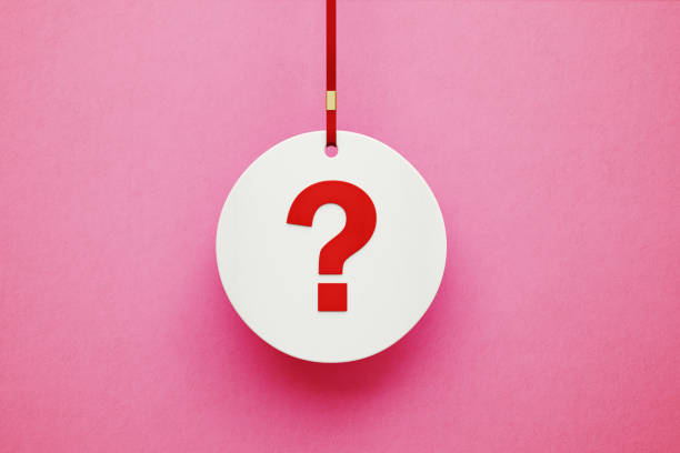 istock Question Mark on White Circle Label Hanging from Red Ribbon over Pink Background 1204469981