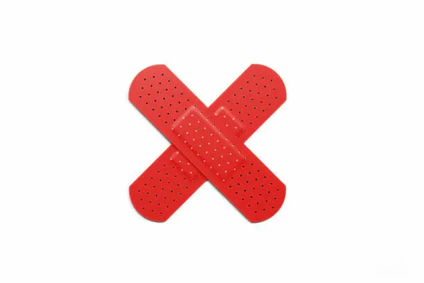 Red adhesive bandage plasters forming a cross on white background, Horizontal composition with clipping path.