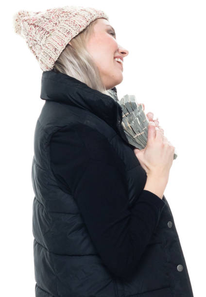 mujer caucásica sin mangas agachada usando ropa de abrigo y sosteniendo la moneda - laughing women us paper currency isolated fotografías e imágenes de stock