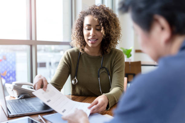 il medico femminile mostra i risultati dei test a pazienti maschi irriconoscibili - doctor radiologist computer latin american and hispanic ethnicity foto e immagini stock