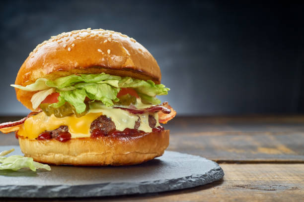 istock Big hamburger on black slate dish over dark background 1204476878