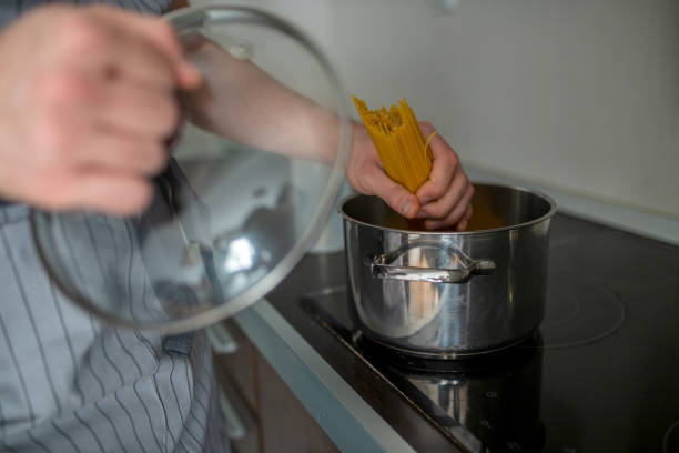 istock Handsome man preparing pasta in the kitchen. Guy cooking a tasty meal. 1204479427