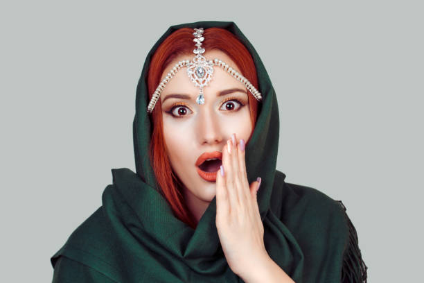 美しいショックを受けたイスラム教徒の女性の女の子は、灰色の背景に隔離された頭の上にカメラグリーンヒジャーブスカーフとティッカジュエリーを見て開いた月に手で大きな目を持つイ� - green tika ストックフォトと画像