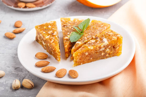 istock Traditional turkish candy cezerye made from caramelised melon, roasted walnuts, hazelnuts, cashew, pistachios on white ceramic plate and a cup of coffee on a gray concrete background. side view, close up, selective focus. 1204480134