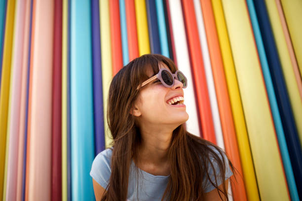 nahaufnahme fröhliche junge frau lacht mit sonnenbrille vor buntem hintergrund - people and lifestyle stock-fotos und bilder