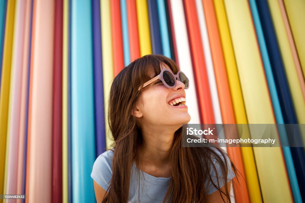 De cerca joven alegre riendo con gafas de sol contra fondo colorido - Foto de stock de Mujeres libre de derechos