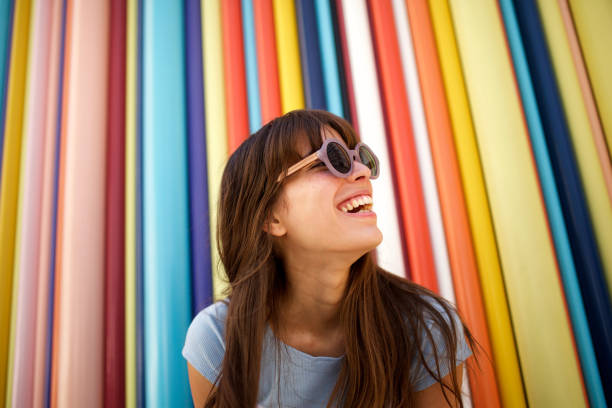 fermez-vous vers le haut de la jeune femme gaie riant avec des lunettes de soleil sur le fond coloré - prise de vue en extérieur photos photos et images de collection