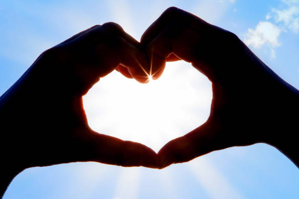 istock Hands forming a heart shape over the sun 1204484234