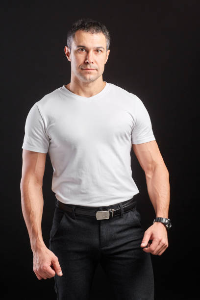 istock Handsome Athletic man in white blank t-shirt standing on black wall background 1204485268