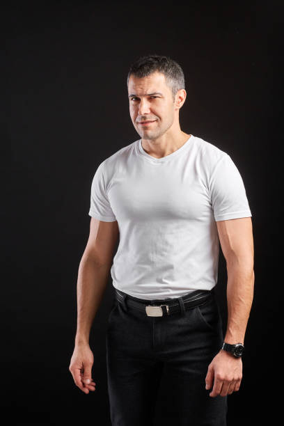 istock Handsome Athletic man in white blank t-shirt standing on black wall background 1204485340