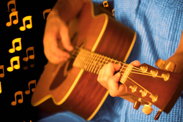 A DSLR photo of a man playing a guitar during a concert. The man is playing an acoustic guitar and wearing a blue shirt, the face is invisible. Musical note shaped bokeh can be seen at the background. It's a REAL bokeh photo, not a computer filter.