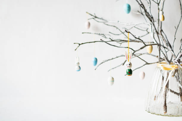 Still life with tree branches decorated with Easter eggs, feathers and bunnies in a glass vase