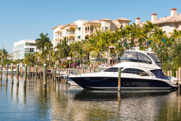 Luxury Boat Docked by Residential Buildings in Las Olas Fort Lauderdale Florida This is a photograph of a luxury boat docked in canal waters behind a residential building surrounded with palm trees by Las Olas in Fort Lauderdale, Florida. moored photos stock pictures, royalty-free photos & images