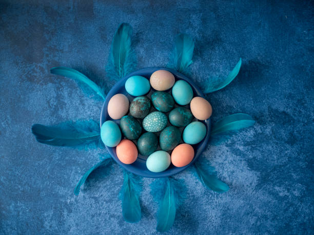 istock Colorful Easter eggs in blue plate and feathers on deep blue background. Easter holiday decorations , Easter concept background. 1204490396