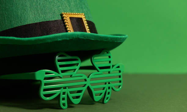 feliz día de san patricio. sombrero de lepriconcon con gafas en forma de trébol de tres hojas sobre un fondo verde. atributos festivos - day patricks st patricks day clover fotografías e imágenes de stock