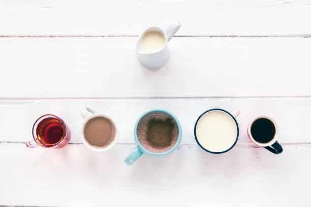 istock Five different hot drinks on white wooden table. Hot chocolate with cinnamon, matcha tea, coffee espresso, tea, latte. Jug of milk. Top view, flat lay. 1204494601