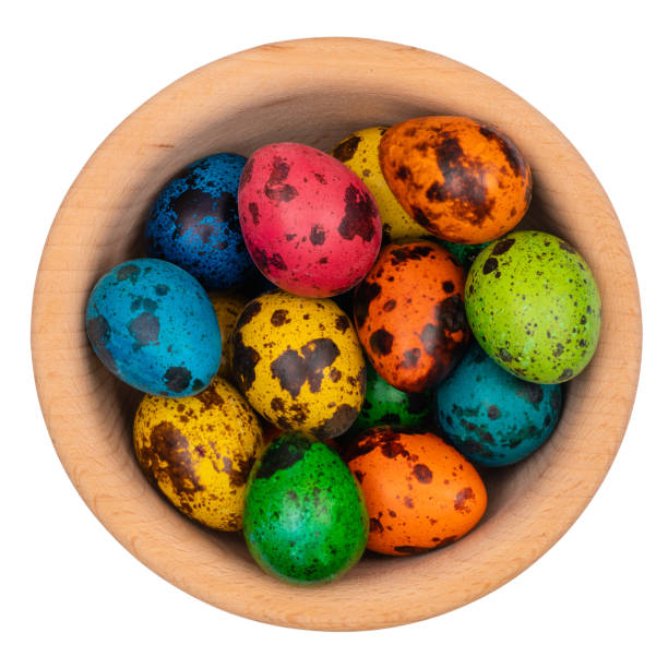 Easter quail eggs in a wooden bowl on a white isolated background.