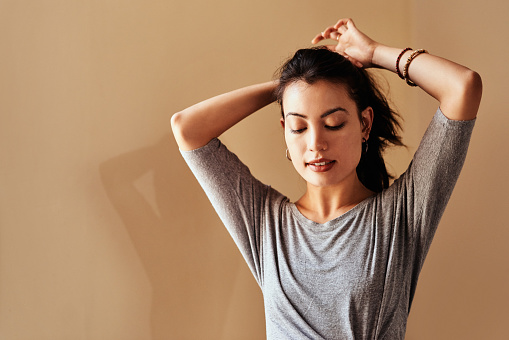 Shot of a young woman tying up her hair in preparation for a yoga session