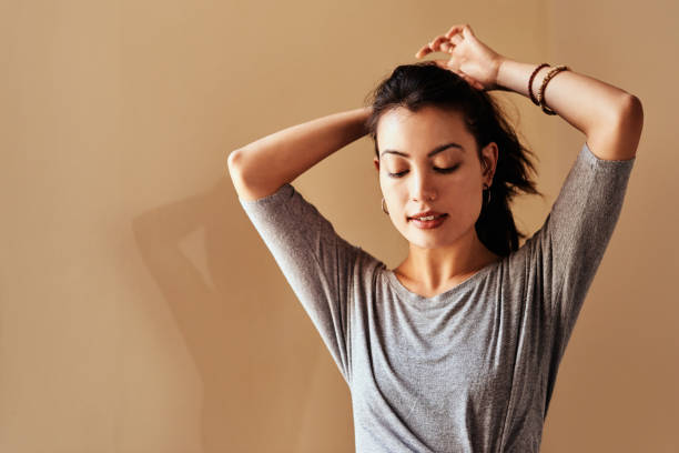 Self betterment begins now Shot of a young woman tying up her hair in preparation for a yoga session woman tying hair in ponytail getting ready for exercising stock pictures, royalty-free photos & images