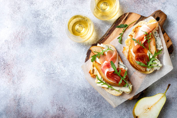 Appetizer crostini, tapas, open faced sandwiches with pear, prosciutto, arugula and blue cheese. Delicious snack, appetizers