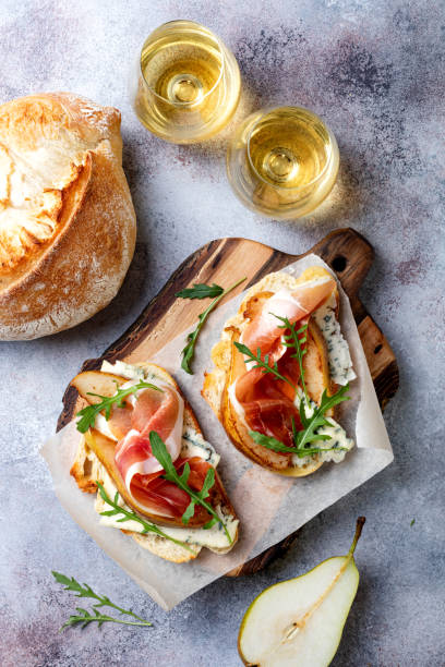 istock Appetizer crostini, tapas, open faced sandwiches with pear, prosciutto, arugula and blue cheese. Delicious snack, appetizers 1204496099