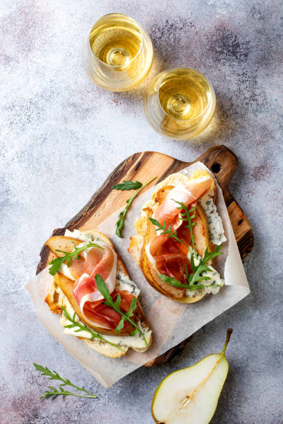 istock Appetizer crostini, tapas, open faced sandwiches with pear, prosciutto, arugula and blue cheese. Delicious snack, appetizers 1204496112