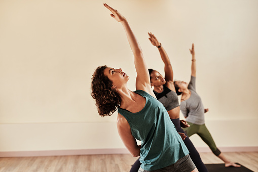 Shot of a group of young men and women practicing yoga in a fitness class