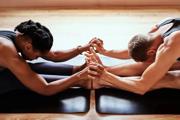 Shot of a young man and woman holding hands during a yoga session