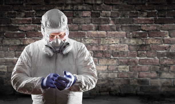 homme utilisant le costume de hazmat, le masque protecteur de gaz et les lunettes contre le mur de brique - tenue stérile photos et images de collection