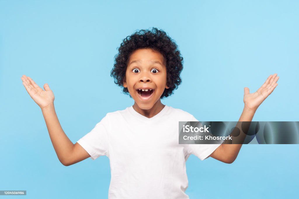 No way, I can't believe! Portrait of funny amazed preschool boy keeping hands up in astonishment No way, I can't believe! Portrait of funny amazed preschool boy keeping hands up in astonishment, looking surprised and sarcastic at camera, excited shocked by sudden news. studio shot blue background Child Stock Photo
