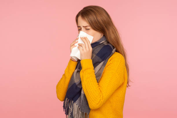 temporada de gripe. retrato de chica de pelo rojo poco saludable usando bufanda grande, estornudos y soplando la nariz, limpiando con tejido - kleenex yellow white pink fotografías e imágenes de stock