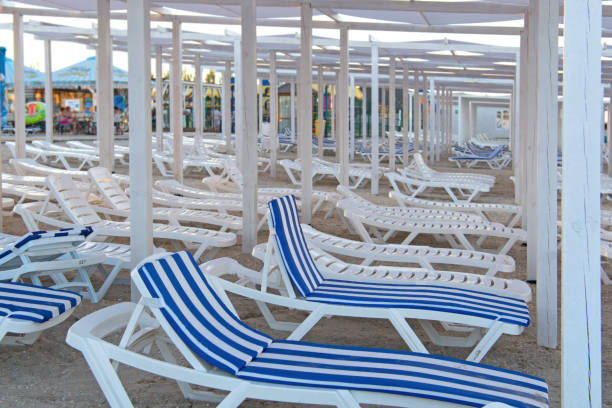 istock Lots of beach plastic white sun loungers. 1204507229