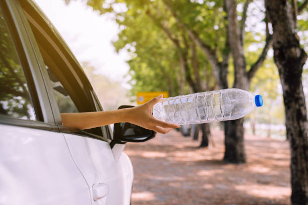 istock Woman hand throwing plastic bottle trash on the road,Environment and pollution campaign concept 1204517979