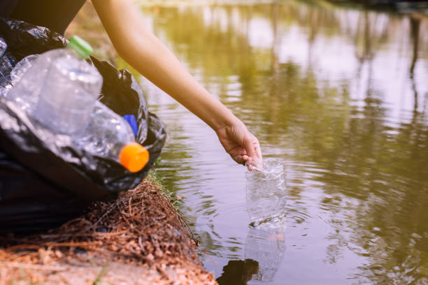 istock Woman volunteer picking up a bottle plastic trash in river,Environment and pollution campaign concept 1204522654