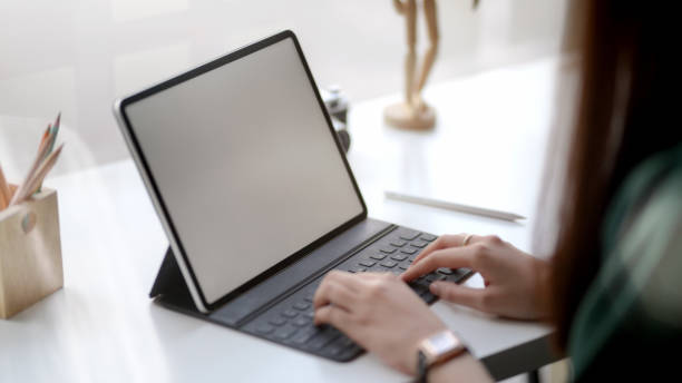 istock Close up view of female designer typing on blank screen tablet in simple co working space 1204526200