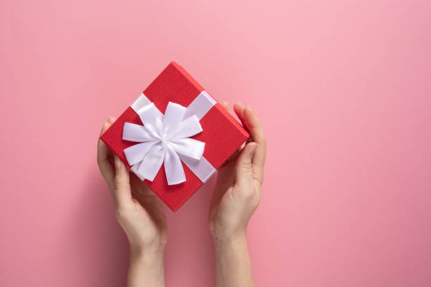 istock Valentine's Day celebration concept. A nice gift from a loved one. Box with a bow in female hands on a delicate pink background. Copy space. Flat lay. 1204526321