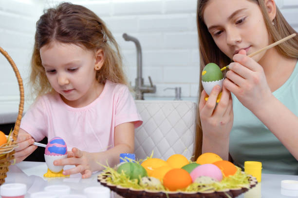 istock Happy easter. Two sisters painting Easter eggs. Happy family children preparing for Easter. Cute little child girl wearing bunny ears on Easter day 1204526494