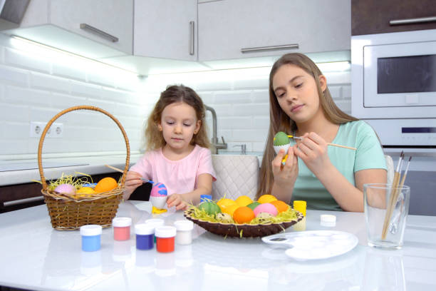 istock Happy easter. Two sisters painting Easter eggs. Happy family children preparing for Easter. Cute little child girl wearing bunny ears on Easter day 1204526498