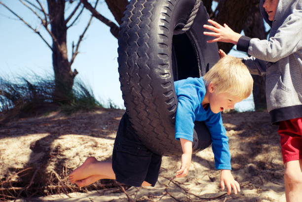 istock Children on Tyre Swing  at Beach 1204533456