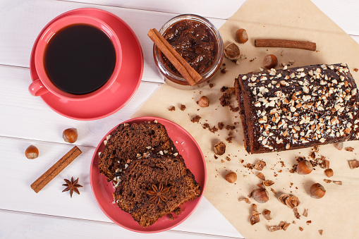 Fresh baked gingerbread or dark cake with cocoa, chocolate and plum jam, cup of black coffee, delicious dessert