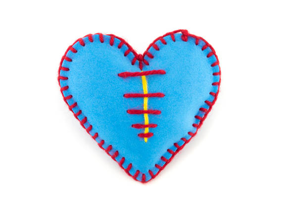 One handmade blue felt stitched toy heart on white background. Love, relationship, Valentines Day, broken heart concept