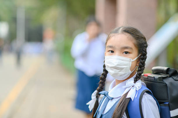 School Girl wearing mouth mask against air smog pollution in Bangkok city, Thailand stock photo